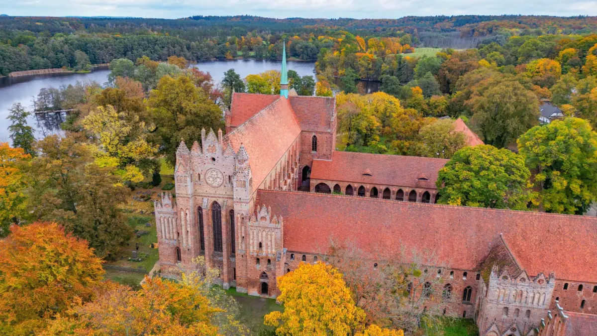 Herbst am Kloster Chorin: 16.10.2025, Brandenburg, Chorin: Herbstlich bunt sind die Laubbäume am Kloster Chorin verfärbt (Luftaufnahme mit einer Drohne). Die Geschichte des Klosters Chorin reicht lange in die Vergangenheit zurück. Das heutige Denkmal mit großer Ausstrahlung über die Region hinaus ist Mönchen zu verdanken, die sich vor 750 Jahren hier niederließen. 1272 wurden erstmals das Zisterzienser in Chorin erwähnt. Die Choriner Klosterkirche wurde zum Vorbild für Kirchen in Berlin, Angermünde und Neubrandenburg. Foto: Patrick Pleul/dpa +++ dpa-Bildfunk +++