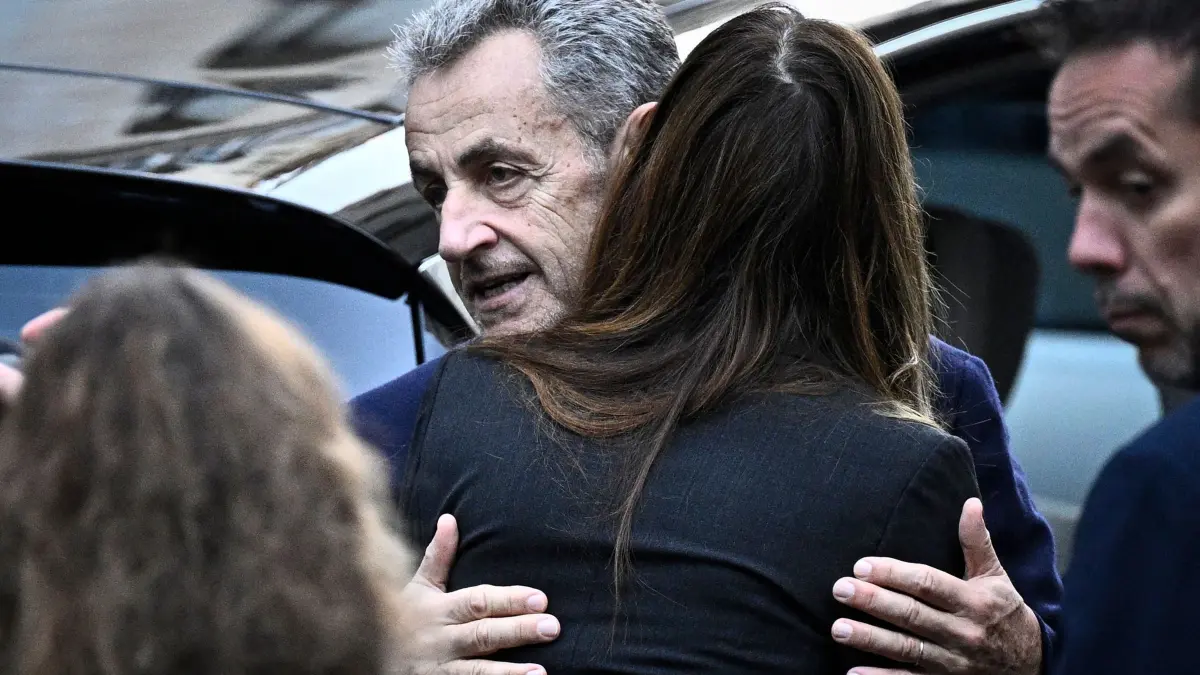Haftantritt von Frankreichs Ex-Präsident Sarkozy: 21.10.2025, Frankreich, Paris: Frankreichs ehemaliger Präsident Nicolas Sarkozy umarmt seine Frau Carla Bruni-Sarkozy, als er seine Residenz verlässt, um sich im Gefängnis La Sante vorzustellen, wo er zu einer fünfjährigen Haftstrafe verurteilt wurde. Der ehemalige französische Präsident Nicolas Sarkozy muss wegen einer kriminellen Verschwörung zur Finanzierung seines Wahlkampfes 2007 mit Geldern aus Libyen ins Gefängnis. Foto: Julien De Rosa/AFP/dpa +++ dpa-Bildfunk +++