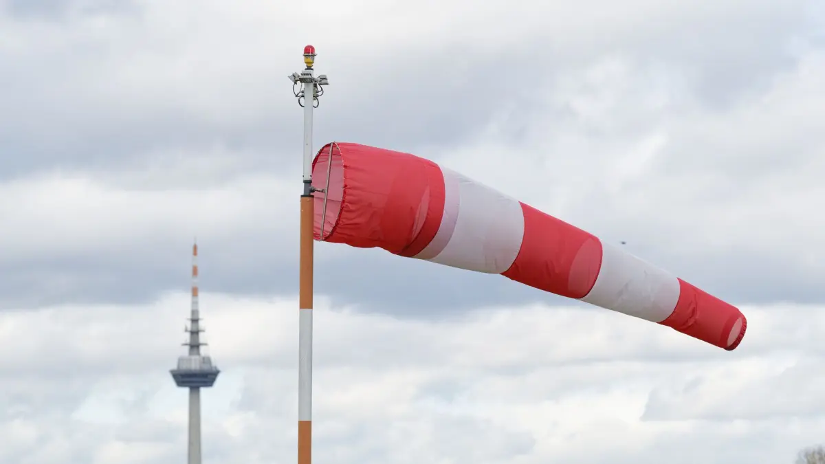 21.10.2025, Baden-Württemberg, Mannheim: Ein Windsack weht am Mannheimer Flughafen im Wind. Im Hintergrund ist der Mannheimer Fernmeldeturm zu sehen. (zu dpa: «Von nass zu nasskalt: Herbst zeigt sich von ruppiger Seite») Foto: Uwe Anspach/dpa +++ dpa-Bildfunk +++