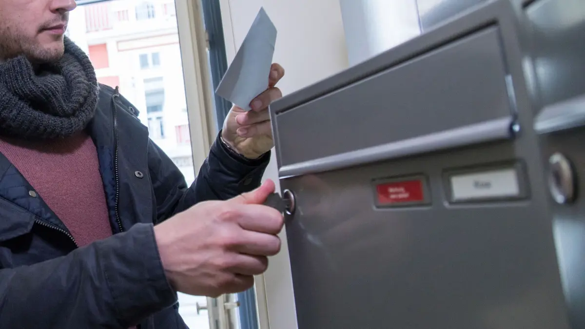 Ein Mann holt einen Brief aus dem Briefkasten