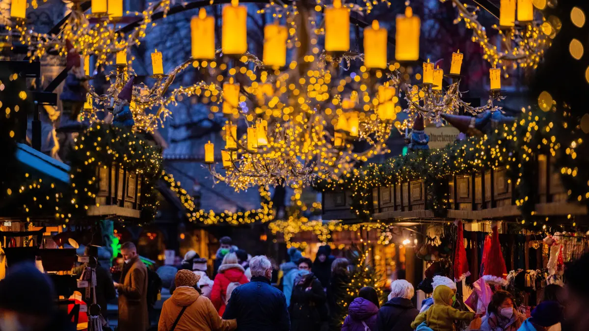 Besucher gehen über den Weihnachtsmarkt am Alter Markt. Die Weihnachtsmärkte in Köln sind für Besucher unter den 2G-Regeln geöffnet. +++ dpa-Bildfunk +++