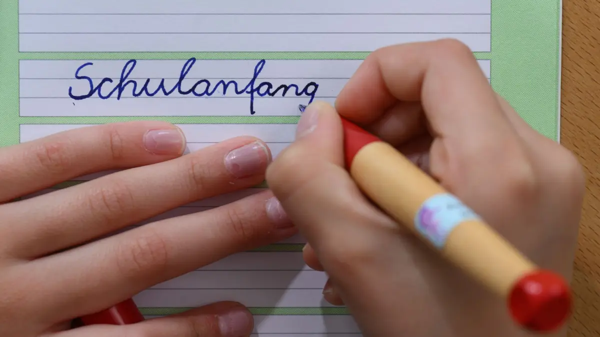 Start ins neue Schuljahr: SYMBOLBILD - 06.08.2025, Sachsen, Leipzig: ILLUSTRATION - Ein Mädchen schreibt das Wort «Schulanfang» in ein Schreibheft. Nach den Sommerferien beginnt am Montag (11.08.2025) in den ersten Bundesländern das neue Schuljahr. (zu dpa: «Einschulungen in Sachsen-Anhalt auf Rekordtief») Foto: Hendrik Schmidt/dpa +++ dpa-Bildfunk +++