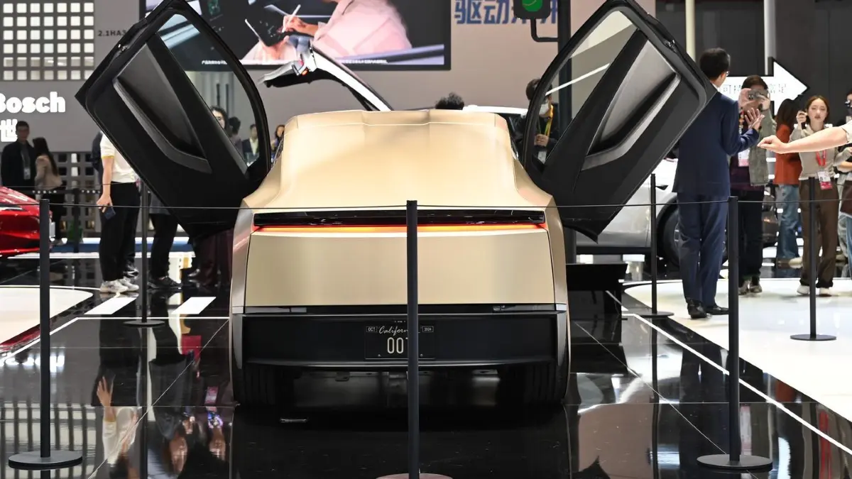 China International Import Expo: 05.11.2025, China, Shanghai: Menschen begutachten auf dem Stand des US-Elektroautobauers Tesla während der China International Import Expo (CIIE) ein goldenes Tesla-Modell. Foto: Johannes Neudecker/dpa +++ dpa-Bildfunk +++