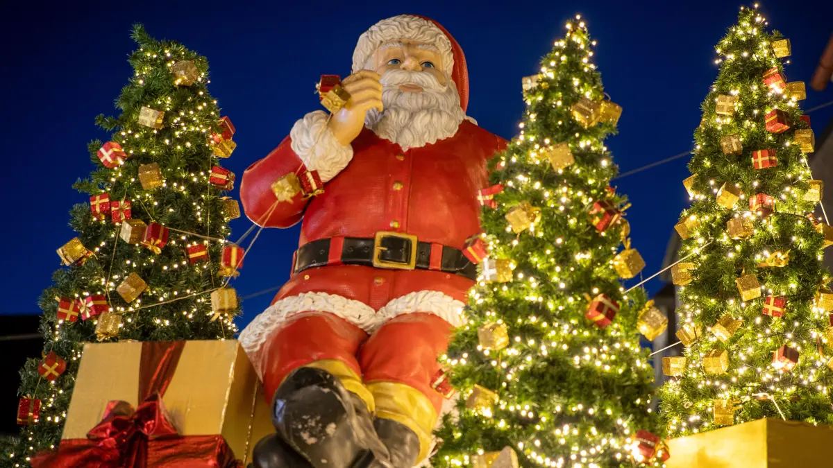 Ein Weihnachtsmann, Geschenke und kleine Weihnachtsbäume schmücken einen Stand auf dem Weihnachtsmarkt. +++ dpa-Bildfunk +++