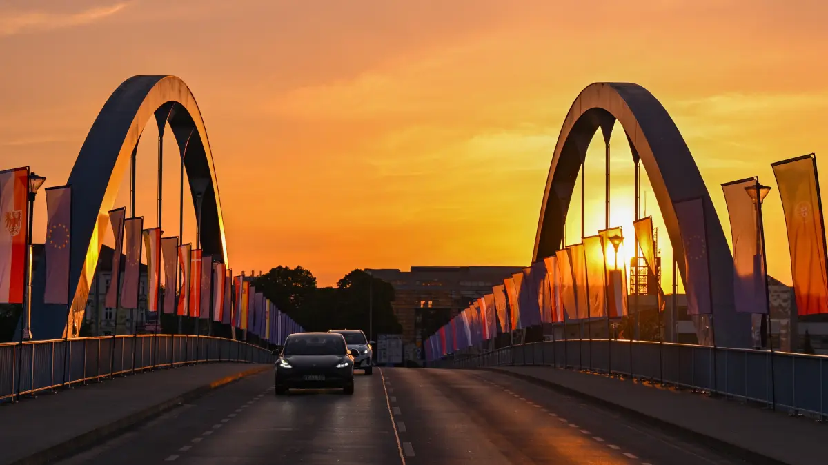 Autos fahren zum Sonnenaufgang über die Stadtbrücke über den Grenzfluss Oder zwischen Frankfurt (Oder) und dem polnischen Slubice.