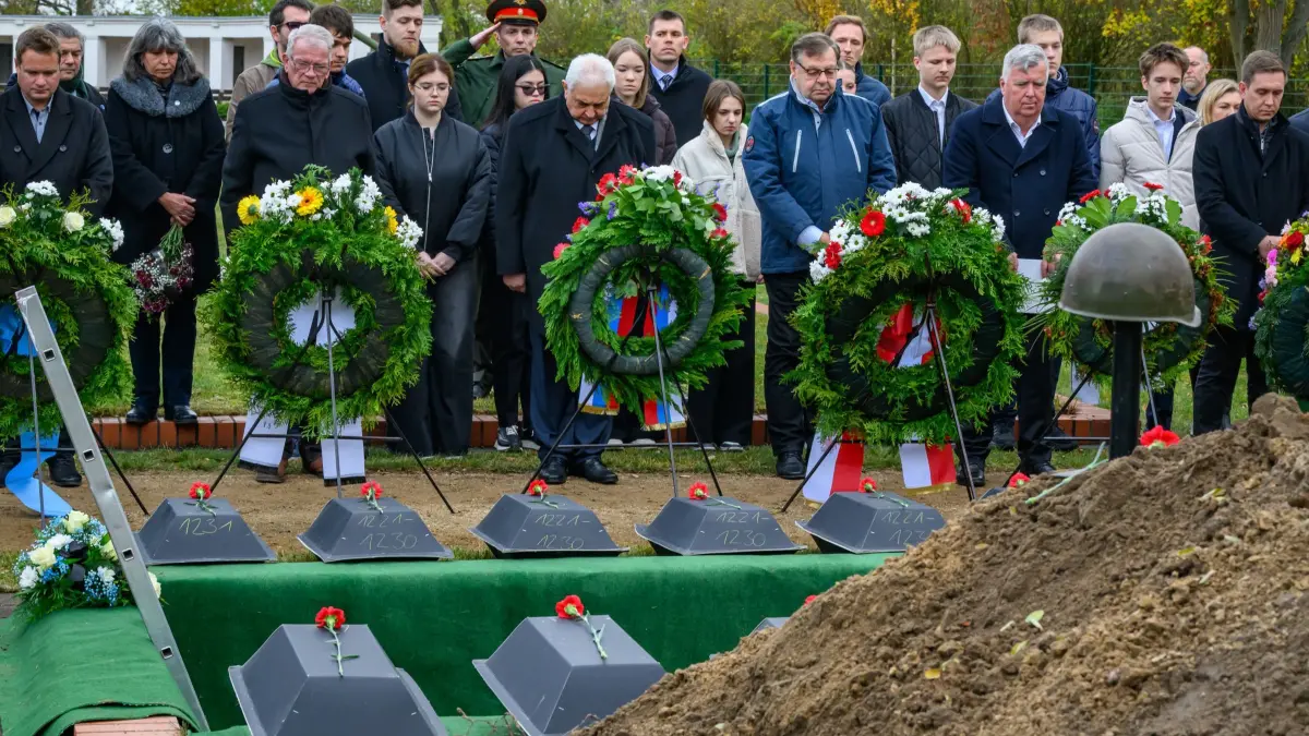 Stille Einbettung von 39 sowjetischen Soldaten: 14.11.2025, Brandenburg, Lebus: Sergej J. Netschajew (hinter dem dritten Kranz v.l.), russischer Botschafter in Deutschland, nimmt mit Gernot Schmidt (3.v.r., SPD), Landrat des Kreises Märkisch-Oderland und weiteren Personen auf der sowjetischen Kriegsgräberstätte an der Einbettung von im Zweiten Weltkrieg gefallenen sowjetischen Soldaten teil. Mit einer stillen Einbettung von 39 sowjetischen Soldaten auf der sowjetischen Kriegsgräberstätte in Lebus (Märkisch-Oderland) erfüllt der Volksbund Deutsche Kriegsgräberfürsorge in Brandenburg seinen humanitären Auftrag. Die Toten wurden in den vergangenen Jahren an verschiedenen Orten in Brandenburg geborgen. Ihre Beisetzung erfolgt im Rahmen des 80. Jahrestages der Kämpfe an der Oder - in jenem Raum, der im Frühjahr 1945 zum Schauplatz schwerster Gefechte wurde. Der Volksbund handelt bei diesen Umbettungen auf Grundlage der völkerrechtlichen Vereinbarungen zwischen Deutschland und der Russischen Föderation über die Kriegsgräberfürsorge. Foto: Patrick Pleul/dpa +++ dpa-Bildfunk +++
