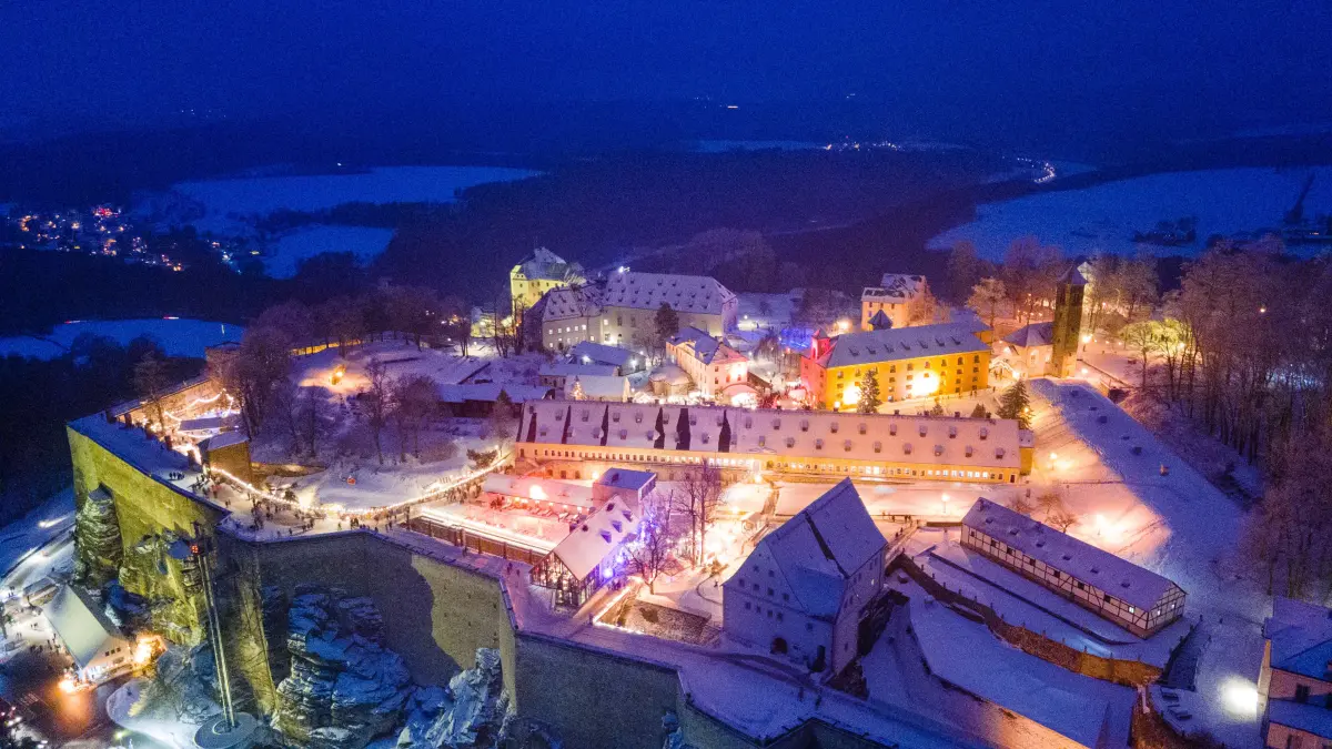 Hell erleuchtet sind die Verkaufsstände auf dem Weihnachtsmarkt auf der Festung Königstein (Luftaufnahme mit einer Drohne). Der historisch-romantische Weihnachtsmarkt findet an allen vier Adventswochenenden statt. +++ dpa-Bildfunk +++