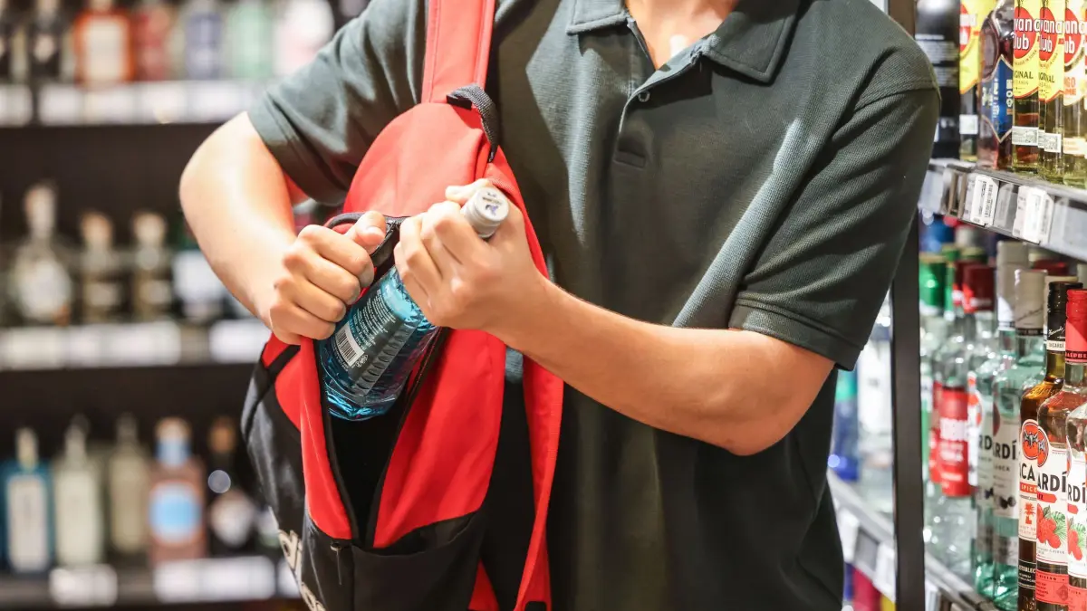 Ladendiebstahl: PRODUKTION - 18.06.2025, Nordrhein-Westfalen, Köln: ILLUSTRATION - Ein Mann steckt in einem Supermarkt eine Flasche mit einem Alkoholhaltigen Getränk in seinen Rucksack. (zu dpa: «Aktionstag in Hessen – Polizei warnt vor Taschendieben») Foto: Oliver Berg/dpa +++ dpa-Bildfunk +++