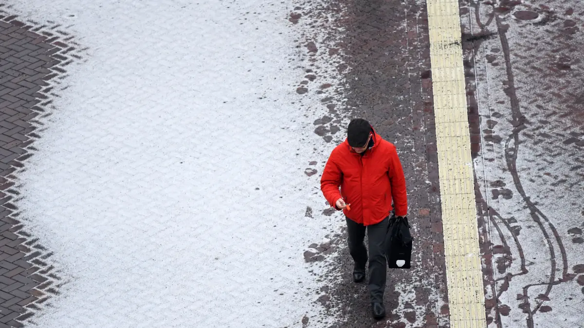Ein Passant ist in Potsdam (Brandenburg) auf einem verschneiten Weg unterwegs.