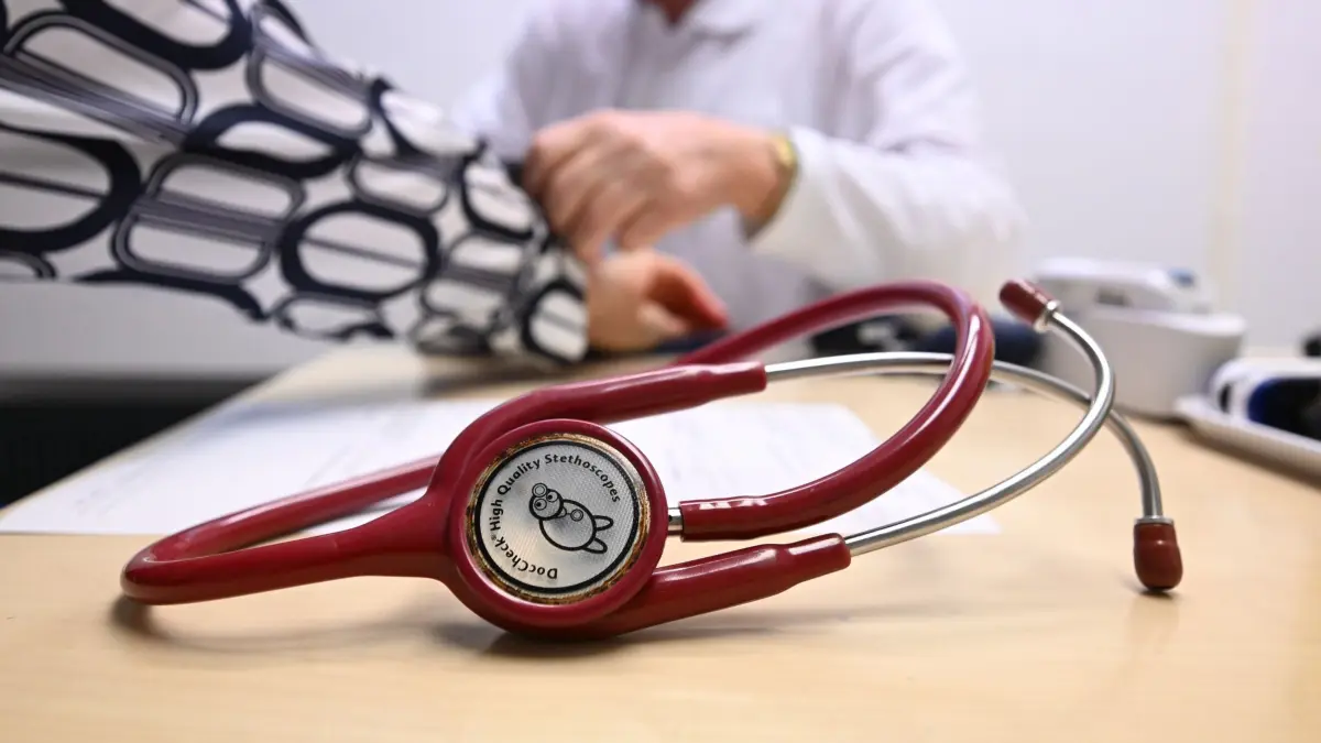 Krankenbehandlung (Symbolfoto): SYMBOLBILD - 16.10.2024, Baden-Württemberg, Leonberg: Ein Arzt misst in einem Untersuchungsraum bei einer Patientin den Blutdruck (gestellte Szene). (zu dpa: «Land muss steigende Gesundheitskosten für Beamte schultern») Foto: Bernd Weißbrod/dpa +++ dpa-Bildfunk +++