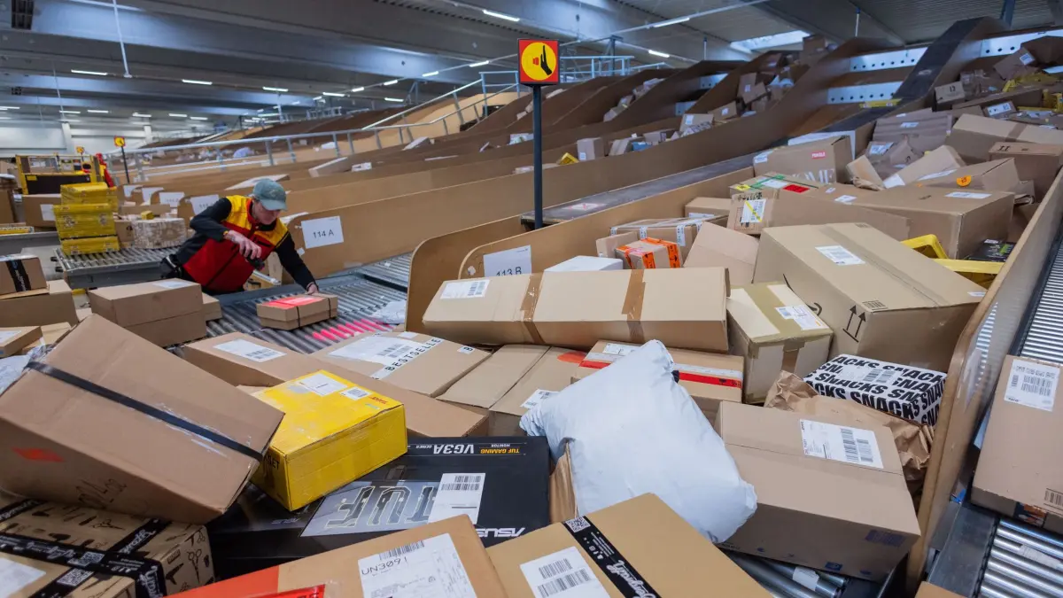 Paketbeförderung in der Vorweihnachtszeit: PRODUKTION - 04.12.2025, Nordrhein-Westfalen, Köln: Ein Paketzusteller sortiert und räumt in einer Zustellbasis von Deutsche Post DHL Pakete in ein Zustellfahrzeug. Aktuell fallen durch den Black Friday (Black Week) und Weihnachten mehr Pakete an. Im diesjährigen Weihnachtsgeschäft rechnet die Deutsche Post DHL wieder mit Paketmassen. Foto: Rolf Vennenbernd/dpa +++ dpa-Bildfunk +++