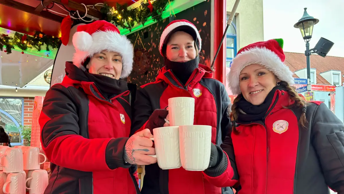 Weihnachtsmarkt 2025 in Fürstenwalde: Irene Seefried, Alexandra Werner und Sabrina Kühnreich (von links) bieten am Stand vom Feuerwehrverein Glühweinspezialitäten aus Dresden an.