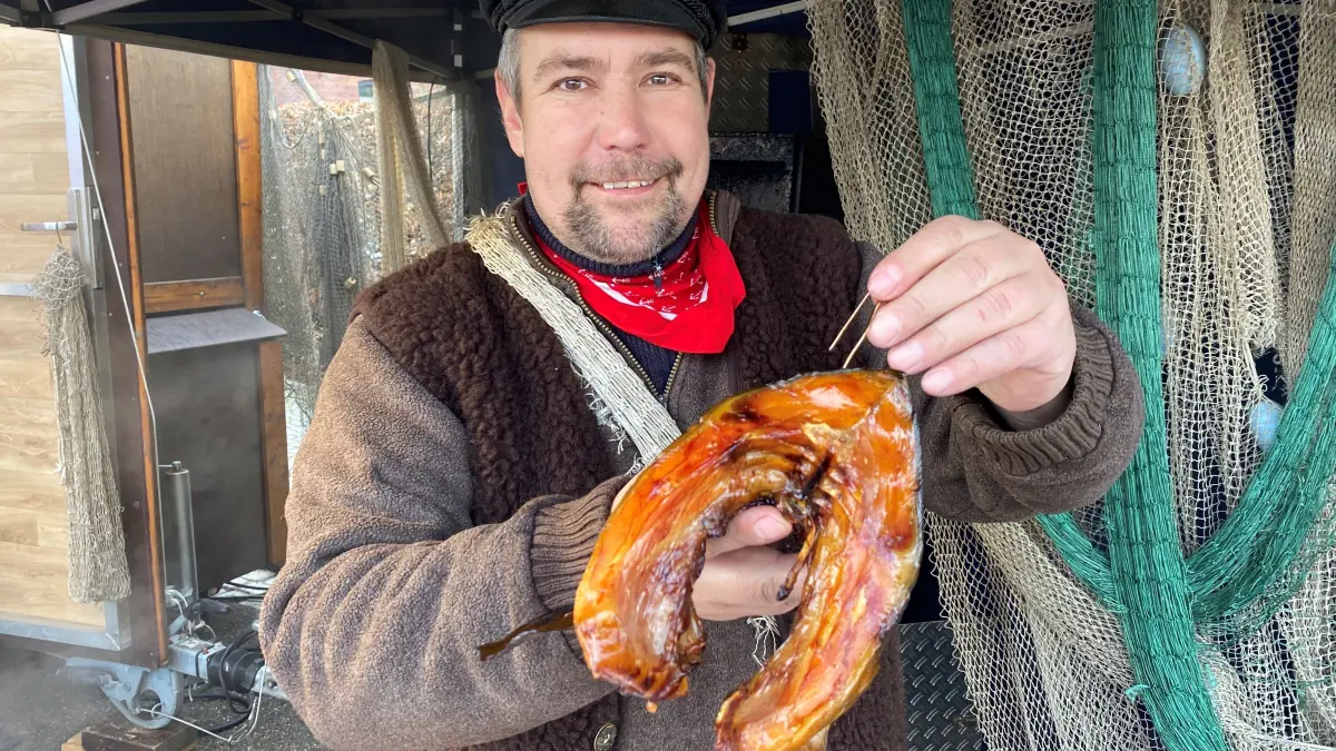 Auf den Weihnachtsmärkten in der Region Eisenhüttenstadt heißbegehrt: Fischer Henry Schneider hat auf dem Weihnachtsmarkt in Neuzelle gerade ein frisch geräuchertes Karbonaden-Stück vom Karpfen aus dem Ofen gezogen.