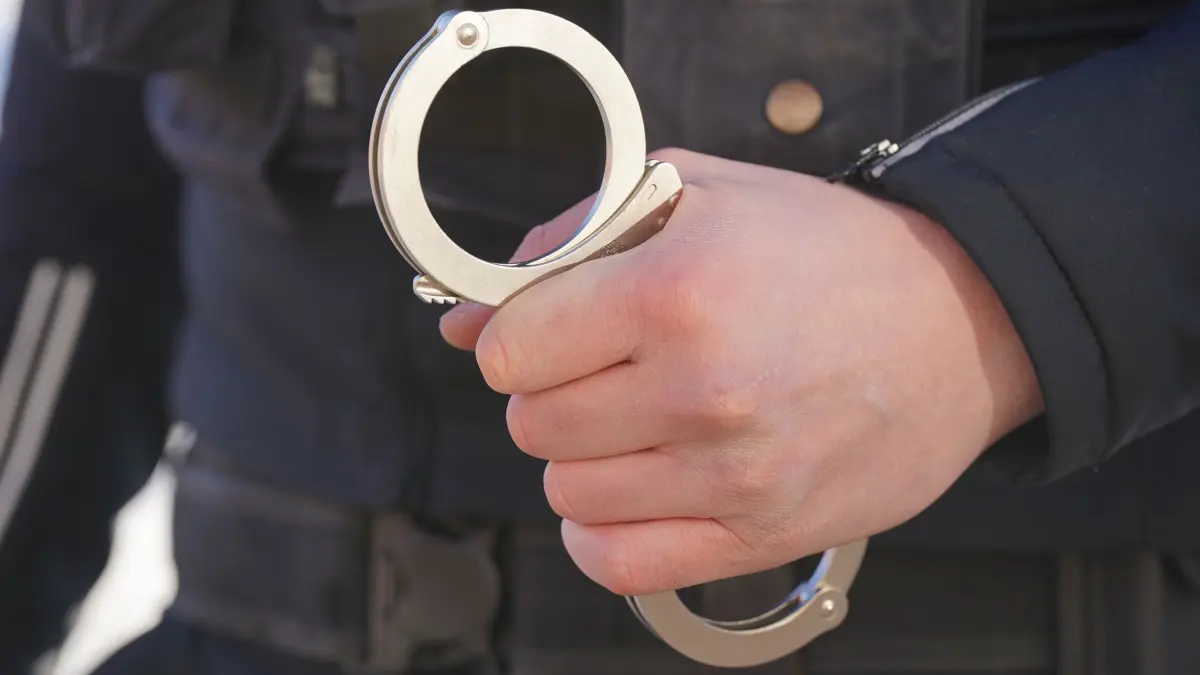 Polizei Handschellen: ARCHIV - 18.01.2024, Mecklenburg-Vorpommern, Schwerin: Ein Polizist hält Handschellen in der Hand. (zu dpa: «Dreistellige Millionengewinne – Razzia gegen Kokaindealer») Foto: Marcus Brandt/dpa +++ dpa-Bildfunk +++