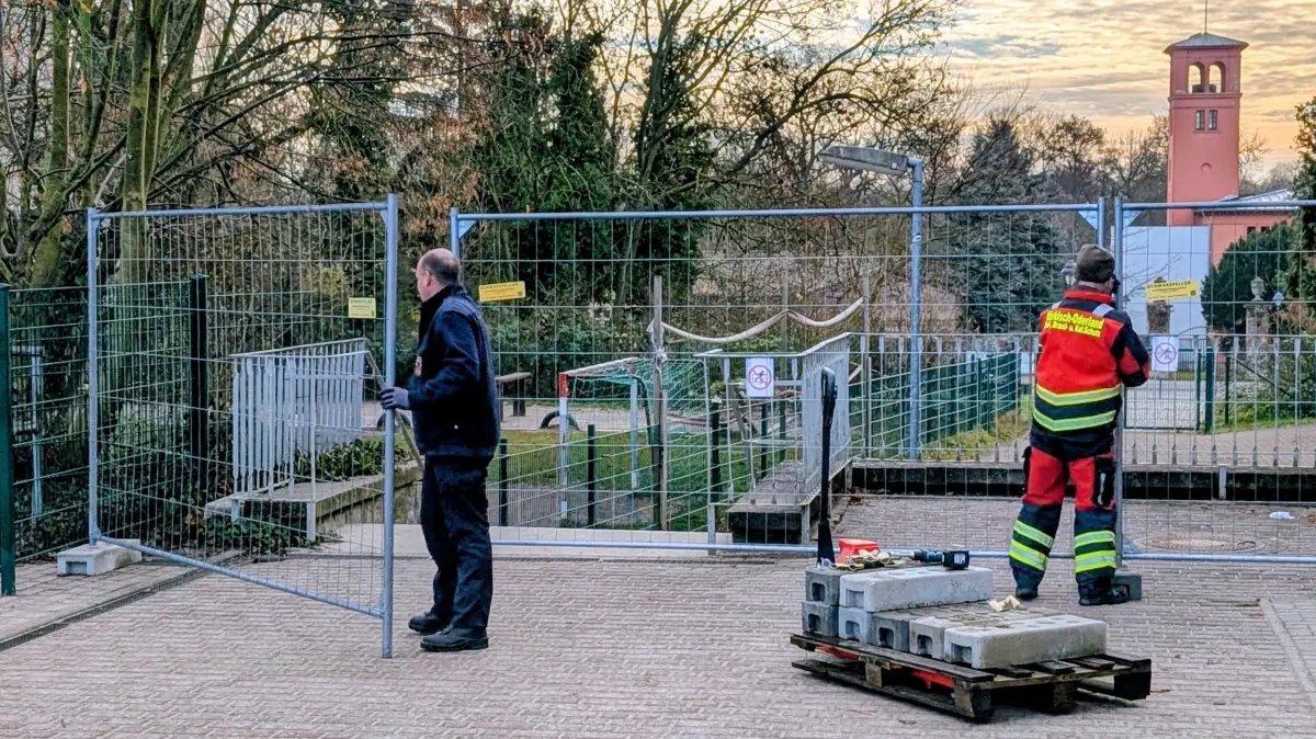 Mitarbeiter des Katastrophenschutzes des Landkreises bauen den Bauzaun auf dem Gelände der Lenné-Schule und des Hortes Kinderkiste auf.