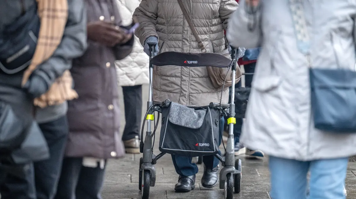 Eine ältere Person mit Rollator geht durch eine belebte Fußgängerzone. Im Bundestag steht am Freitag die Entscheidung über die geplante Rentenreform an, die ein stabiles Rentenniveau, erweiterte Kindererziehungszeiten, steuerfreie Zuverdienstmöglichkeiten im Alter und weitere Änderungen in der Altersvorsorge vorsieht. +++ dpa-Bildfunk +++