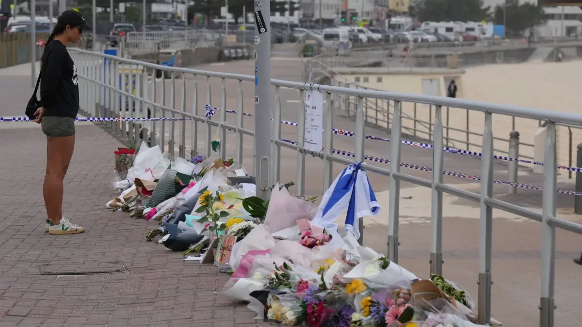 Nach Angriff am Bondi Beach: 16.12.2025, Australien, Sydney: Eine Frau steht am Bondi Beach vor abgelegten Blumen in Gedenken an die Getöteten. Foto: Mark Baker/AP/dpa +++ dpa-Bildfunk +++