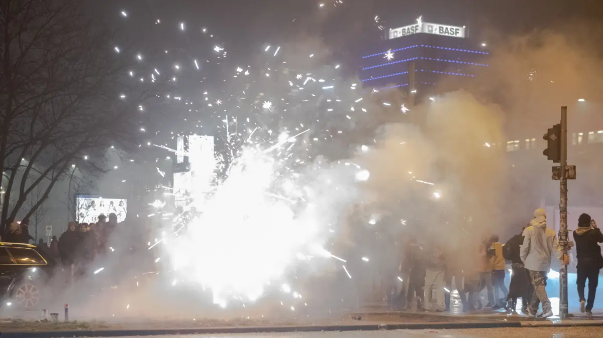 01.01.2019, Berlin: Böller und Raketen steigen auf der Straße an der Oberbaumbrücke in die Luft, während Passanten vorbeigehen. Foto: Paul Zinken/dpa +++ dpa-Bildfunk +++