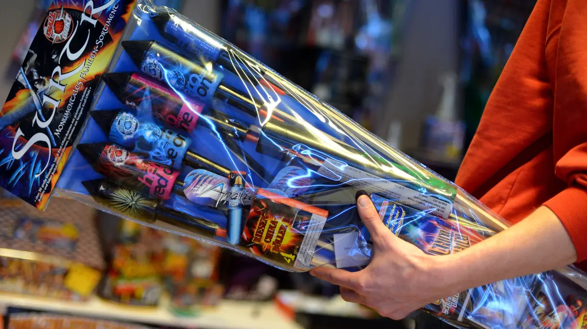 Ein Verkäufer reicht am 28.12.2012 in einem Geschäft in Berlin Raketen über die Ladentheke. Heute startet der offizielle Verkauf von Feuerwerks- und Knallkörpern. Foto: Britta Pedersen/dpa ++ +++ dpa-Bildfunk +++