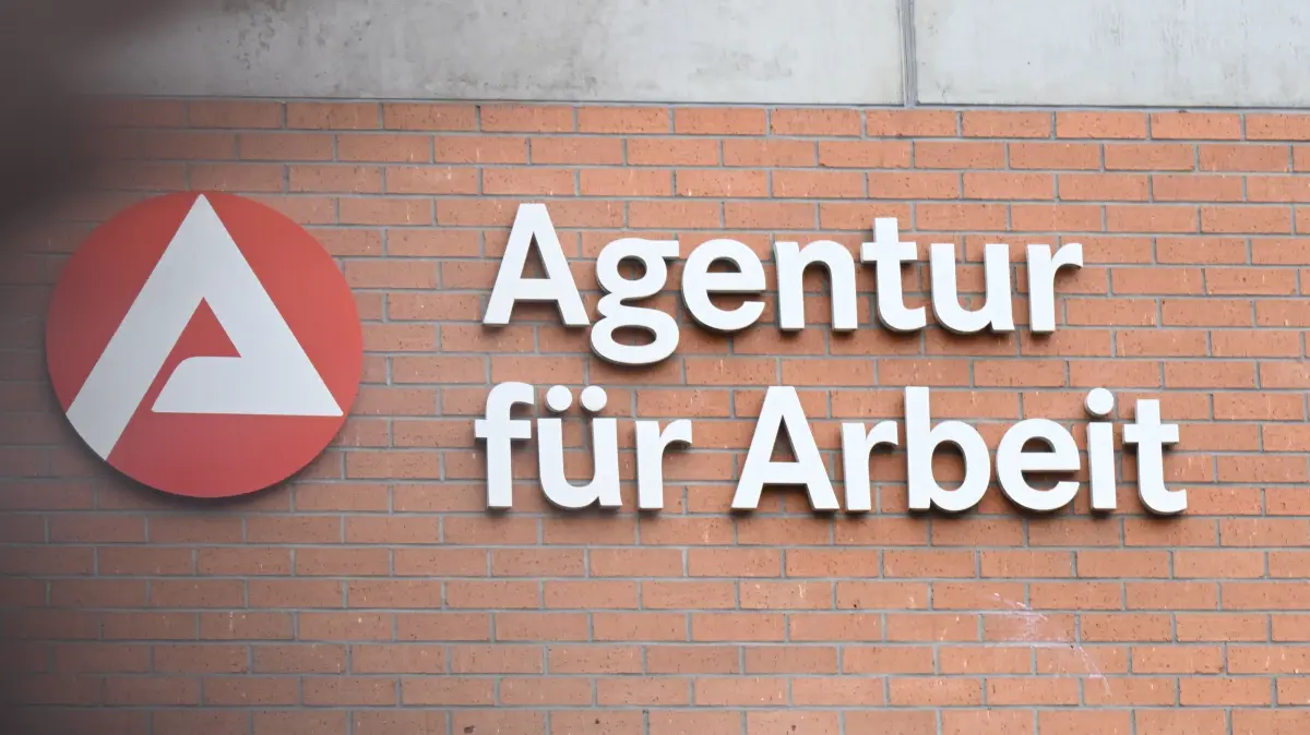 An einem Gebäude der Bundesagentur für Arbeit ist das Logo der Arbeitsagentur angebracht. Davor läuft ein Mensch (Wischeffekt durch Langzeitbelichtung). Die Bundesagentur für Arbeit veröffentlicht am 28.11.2025 ihren Arbeitsmarktbericht für Monat November 2025. +++ dpa-Bildfunk +++