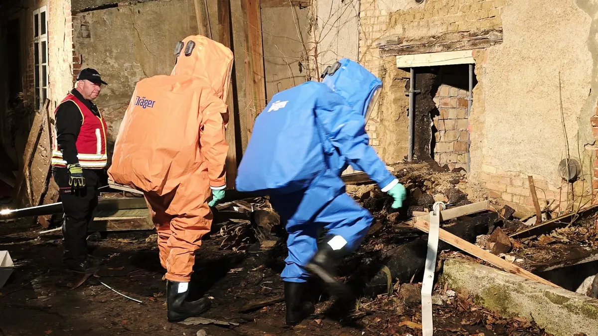 Einsatzkräfte in Chemikalienschutzanzügen dringen in den zuvor geöffneten Raum vor. Feuerwehr, Technisches Hilfswerk und die Gefahrstoffeinheit untersuchen ein altes Gebäude in Gerswalde nach einem ungewöhnlichen Gasgeruch.