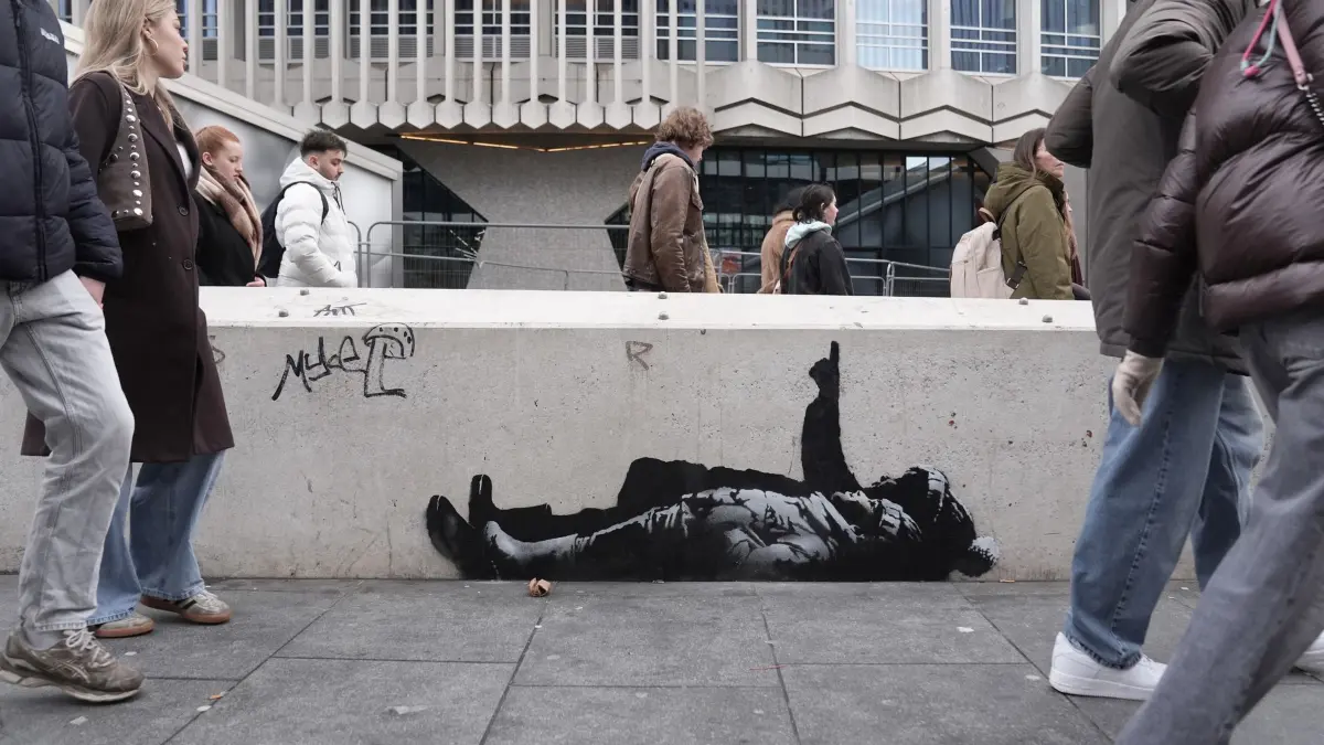 Graffiti-Kunstwerk in London: 22.12.2025, Großbritannien, London: Ein Graffiti-Kunstwerk, das zwei Personen darstellt und möglicherweise vom Straßenkünstler Banksy stammen könnte, wurde unterhalb des Centre Point-Gebäudes in der Nähe der Tottenham Court Road im Zentrum Londons gemalt. Foto: Stefan Rousseau/PA Wire/dpa +++ dpa-Bildfunk +++