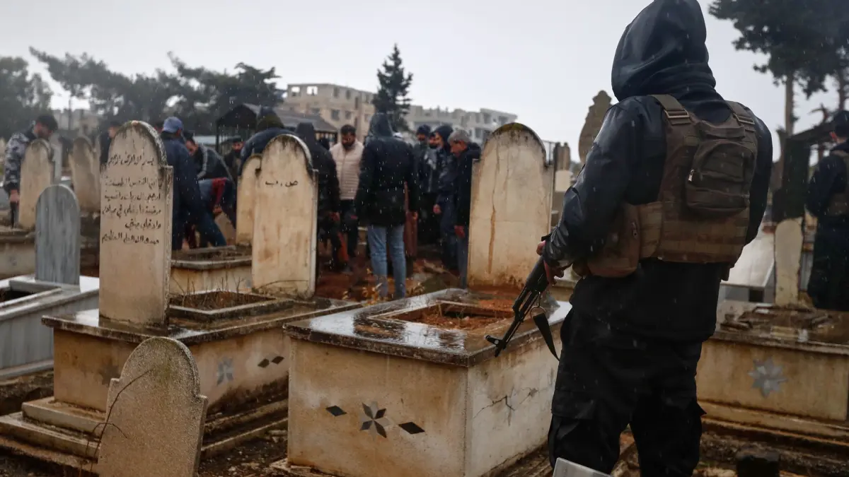 Nach Anschlag auf Moschee in Syrien - Beerdigung: 27.12.2025, Syrien, Homs: Ein syrischer Sicherheitsbeamter bewacht das Gelände während der Beerdigung der Opfer eines Anschlags vom Vortag in der Moschee Imam Ali bin Abi Talib im überwiegend alawitischen Viertel Wadi al-Dhahab auf einem Friedhof am Stadtrand von Homs. Foto: Omar Sanadiki/AP/dpa +++ dpa-Bildfunk +++