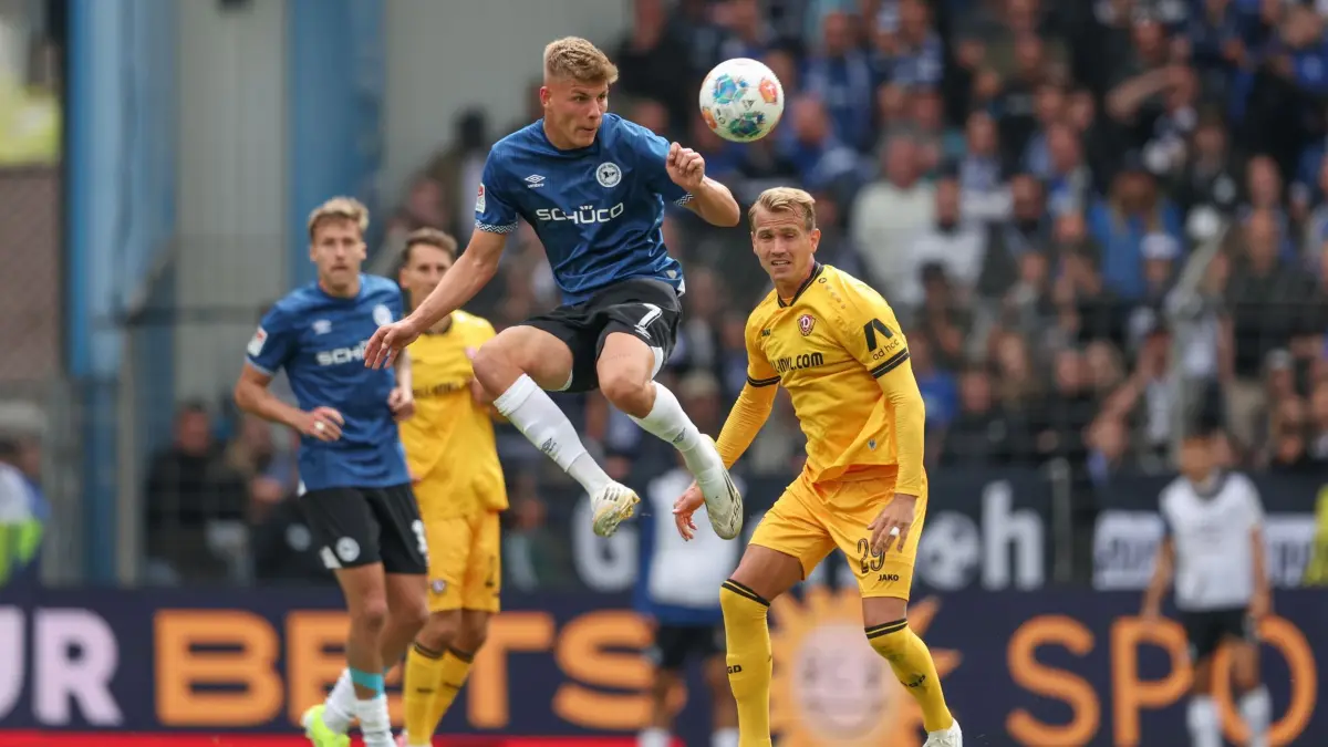 Julian Kania: ARCHIV - 24.08.2025, Nordrhein-Westfalen, Bielefeld: Fußball: 2. Bundesliga, Arminia Bielefeld - Dynamo Dresden, 3. Spieltag, SchücoArena. Julian Kania (l, Arminia Bielefeld) und Lukas Boeder (r, Dynamo Dresden) im Kampf um den Ball. Kania wechselt zum VfL Osnabrück. (zu dpa: «Bielefeld-Stürmer Kania wechselt nach Osnabrück») Foto: Friso Gentsch/dpa +++ dpa-Bildfunk +++