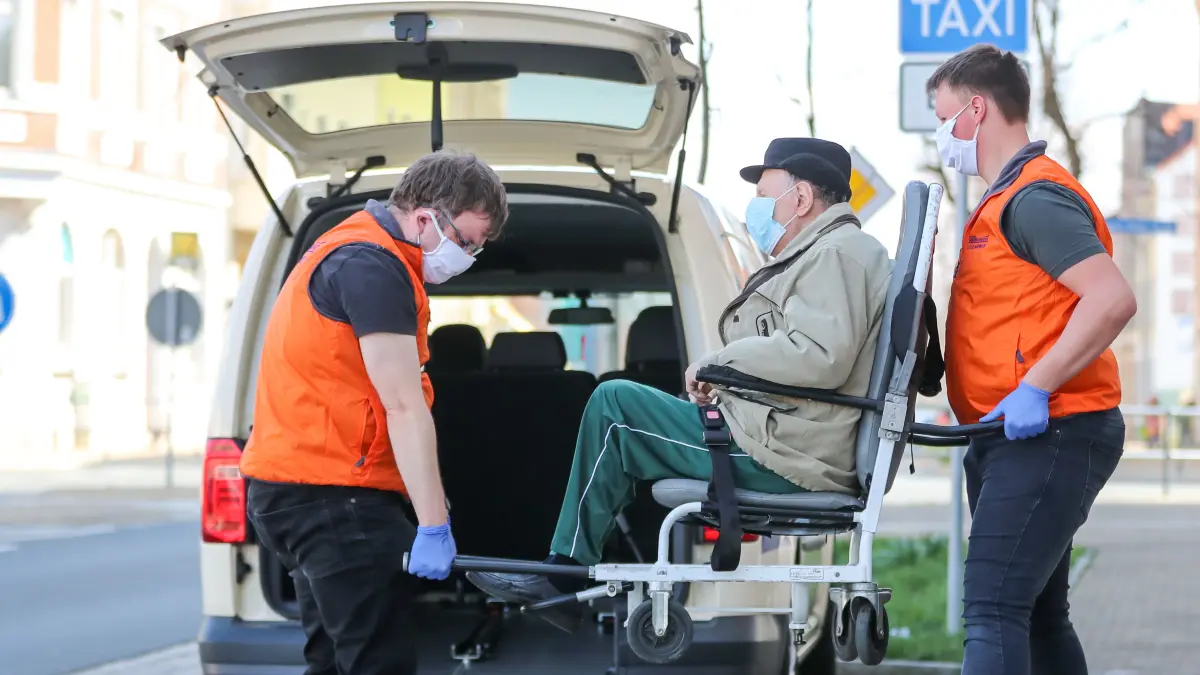Mitarbeiter eines Taxi-Unternehmens bringen einen älteren Herrn nach einer Behandlung mit einem Taxi nach Hause. In Brandenburg fordern Transport-Unternehmen, Verbände wie Johanniter und DRK mehr Geld von den Krankenkassen. (Symbolbild)