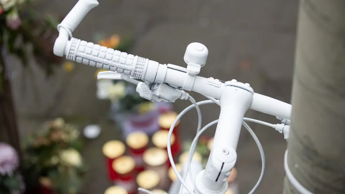 Geisterräder weisen auf getötete Radfahrer hin: ARCHIV - 17.12.2021, Niedersachsen, Osnabrück: Ein sogenanntes „Ghostbike“ und Trauerkerzen stehen als Mahnmal an einer viel befahrenen Straße der Stadt. Mehrere komplett weiß lackierte Fahrräder stehen an Stellen, an denen Radler tödlich verunglückt waren. (zu dpa: «Weniger Verkehrstote in Hamburg - darunter elf Radfahrer») Foto: Friso Gentsch/dpa +++ dpa-Bildfunk +++