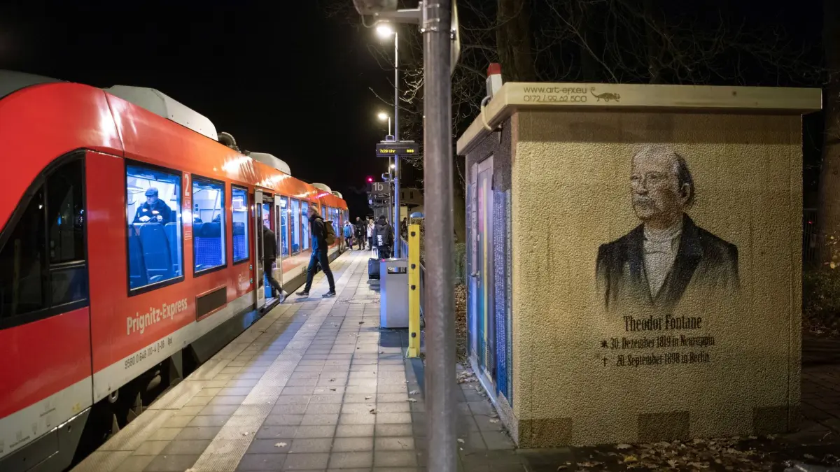 Landkreis fordert Ausbau der Bahnstrecke nach Berlin: ARCHIV - 28.11.2019, Brandenburg, Neuruppin: Die Wand eines kleinen Gebäudes auf dem Bahnhof Rheinsberger Tor in der Fontanestadt Neuruppin im Landkreis Ostprignitz-Ruppin zeigt das Graffiti des Dichters Theodor Fontane und dessen Geburts- und Sterbedatum. Abfahrtbereit steht der Prignitz-Express in Richtung Berlin auf Bahnsteig 1. (zu dpa: «Landkreis fordert halbstündigen Bahntakt nach Berlin») Foto: Soeren Stache/dpa-Zentralbild/dpa +++ dpa-Bildfunk +++