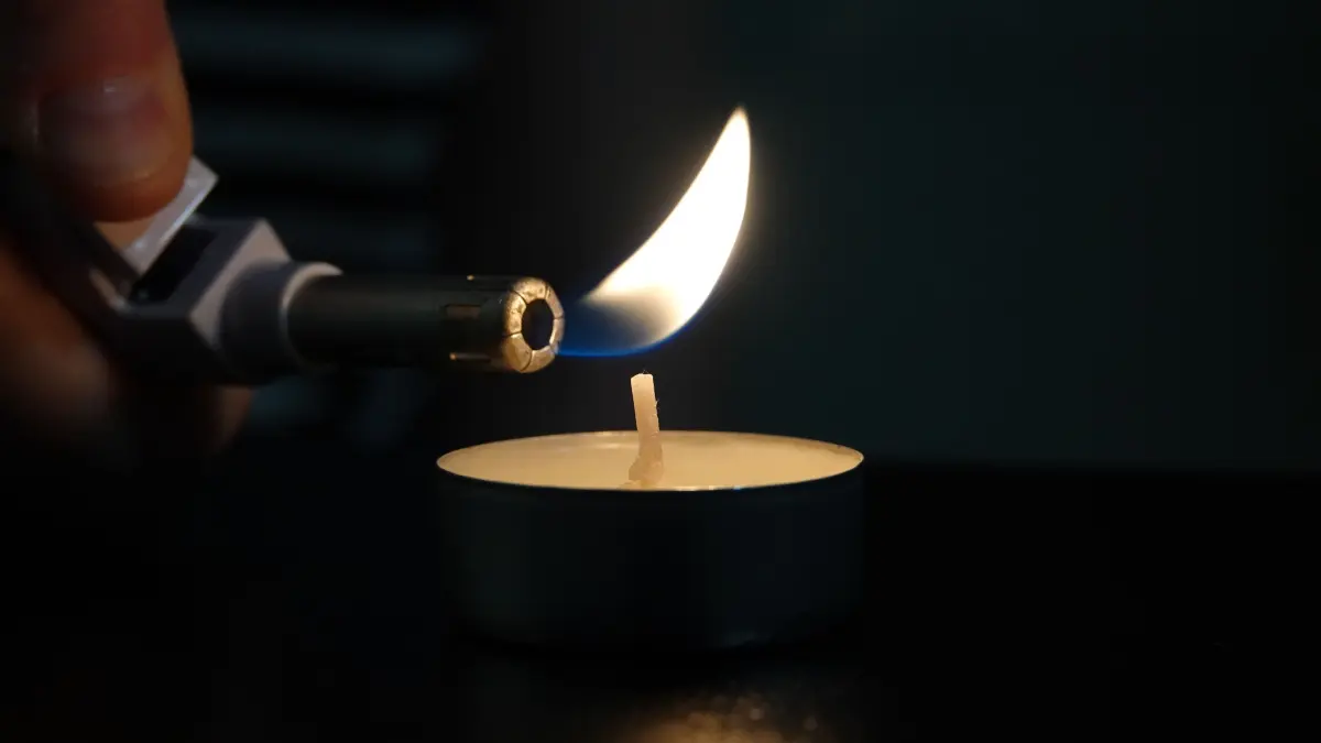 Eine Frau zündet mit einem Feuerzeug ein Teelicht an. (Illustration zu dpa: «Expertin: Irland steuert auf schwere Energiekrise mit Blackouts zu») +++ dpa-Bildfunk +++