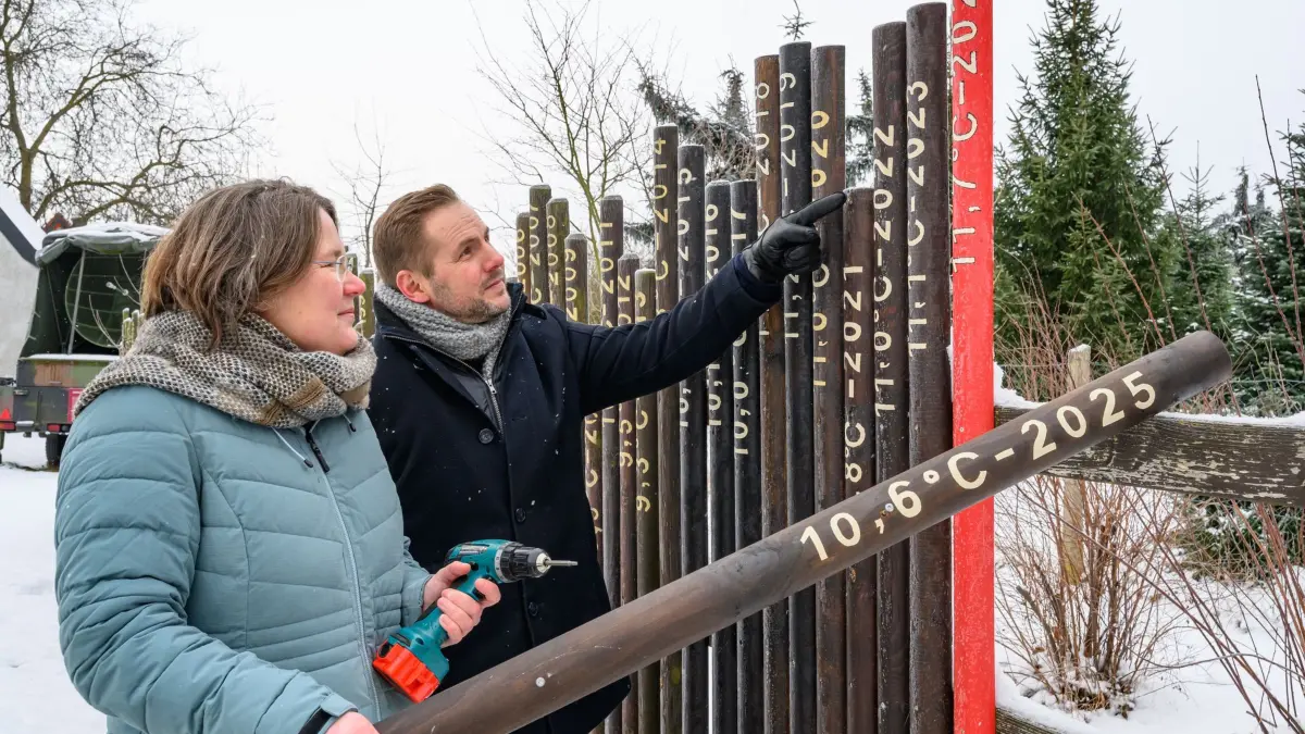 Bundestagsabgeordnete Lübcke besucht Deutschen Wetterdienst: 06.01.2026, Brandenburg, Lindenberg: Andrea Lübcke (Bündnis 90/Die Grünen), Brandenburger Bundestagsabgeordnete und Mitglied im Ausschuss für Forschung, Technologie, Raumfahrt und Technikfolgenabschätzung und David Gornickel, Geschäftsführer vom Wettermuseum, befestigen gemeinsam eine neue Latte am Klimazaun. Die Politikerin besuchte am selben Tag das Wettermuseum und den Deutschen Wetterdienst. Im Wettermuseum brachte Lübcke als diesjährige Patin eine neue Latte am Klimazaun an. Der Klimazaun visualisiert die Entwicklung der Jahresmitteltemperaturen in Lindenberg auf Basis einer der längsten zusammenhängenden Wetterdatenreihen Deutschlands. Jedes Jahr ergänzt eine neue Latte die Darstellung und macht den langfristigen Temperaturanstieg und damit den Klimawandel sichtbar. Foto: Patrick Pleul/dpa +++ dpa-Bildfunk +++