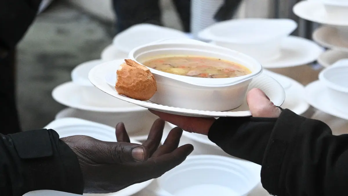Wiedereröffnung der Caritas-Ambulanz am Zoo Berlin: 07.01.2026, Berlin: Eine Helferin gibt bei der Wiedereröffnung der Caritas-Ambulanz am Zoo für wohnungslose Menschen heiße Suppe aus. Seit 1992 versorgt die Caritas-Ambulanz kostenlos obdachlose und nicht krankenversicherte Menschen. Sie kehrt nach längerer Renovierungszeit aus ihrem Ausweichquartier zum früheren Platz zurück. Foto: Jens Kalaene/dpa +++ dpa-Bildfunk +++