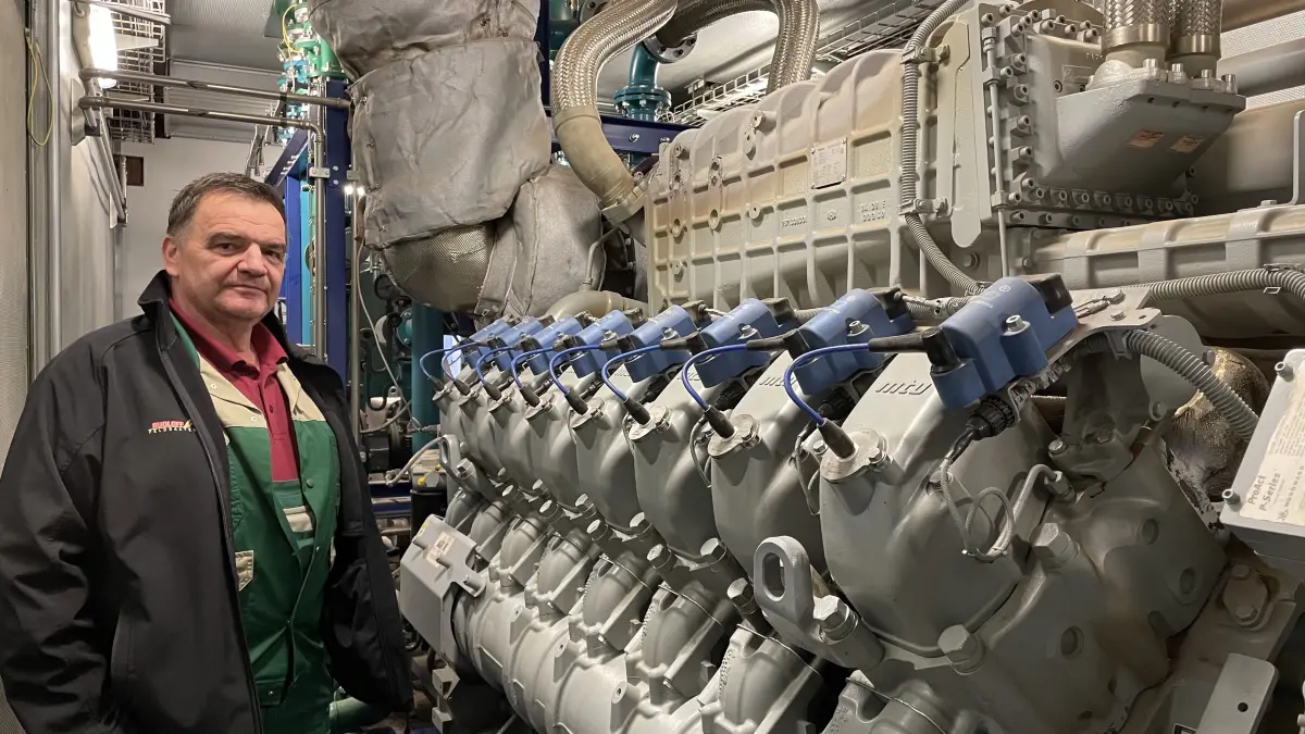 Hartmut Noppe, Geschäftsführer der Agrarprodukte Sauen, neben dem von e.dis aufgestellten Flex-BHKW mit imposantem 16-Zylinder-Motor.