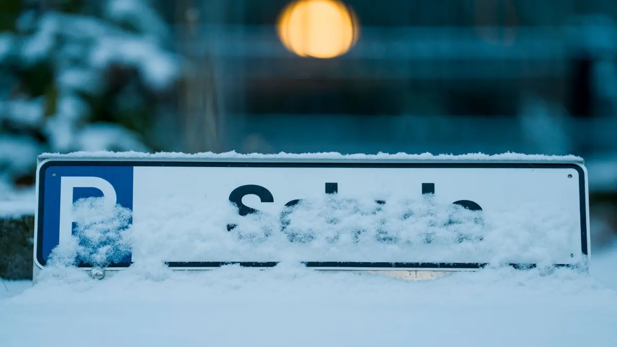 Winterwetter in Hessen: 12.01.2026, Hessen, Frankfurt/Main: Die Parkplatzmarkierung „Schule“ an der Hermann-Herzog-Schule ist eingeschneit, hier fällt der Präsenzunterricht aus. Schnee und Glätte führen in mehreren hessischen Landkreisen zu Unterrichtsausfall oder Distanzunterricht am ersten Schultag nach den Weihnachtsferien. Foto: Andreas Arnold/dpa +++ dpa-Bildfunk +++