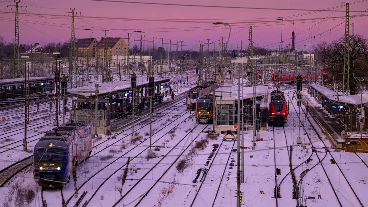 Winterwetter in Brandenburg: 12.01.2026, Brandenburg, Cottbus: Farbig leuchtet der Morgenhimmel zum Sonnenaufgang über dem winterlich verschneiten Gleisen vom Cottbuser Hauptbahnhof. Strenger Frost und Glätte bestimmen das Wetter in Berlin und Brandenburg. Der Montag startet sehr kalt mit Temperaturen zwischen -9 und -15 Grad, lokal bis -20 Grad, wie der Deutsche Wetterdienst mitteilte. Foto: Patrick Pleul/dpa - Honorarfrei nur für Bezieher des Dienstes ZB-Funkregio Ost +++ ZB-FUNKREGIO OST +++