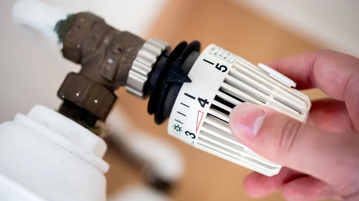 CO2-Preis ab 2028 EU-weit einheitlich: ARCHIV - 04.10.2021, Niedersachsen, Hannover: ILLUSTRATION - Ein Mann dreht in einer Wohnung am Thermostat einer Heizung. (zu dpa: «CO2-Preis bald europaweit: Was macht das mit den Heizkosten?») Foto: Hauke-Christian Dittrich/dpa +++ dpa-Bildfunk +++