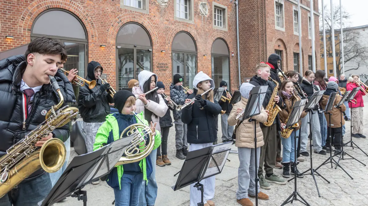 Kinder der Musikschule musizieren in der Kälte vor dem Rathaus.