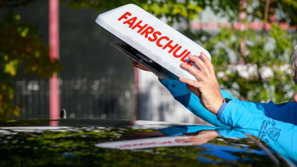 Fahrschule: ARCHIV - 25.08.2025, Sachsen-Anhalt, Magdeburg: "Fahrschule" ist auf einem Schild zu lesen, das ein Fahrlehrer auf das Dach seines Autos stellt. (zu dpa: «Fahrlehrer protestieren gegen Führerschein-Reform») Foto: Klaus-Dietmar Gabbert/dpa +++ dpa-Bildfunk +++