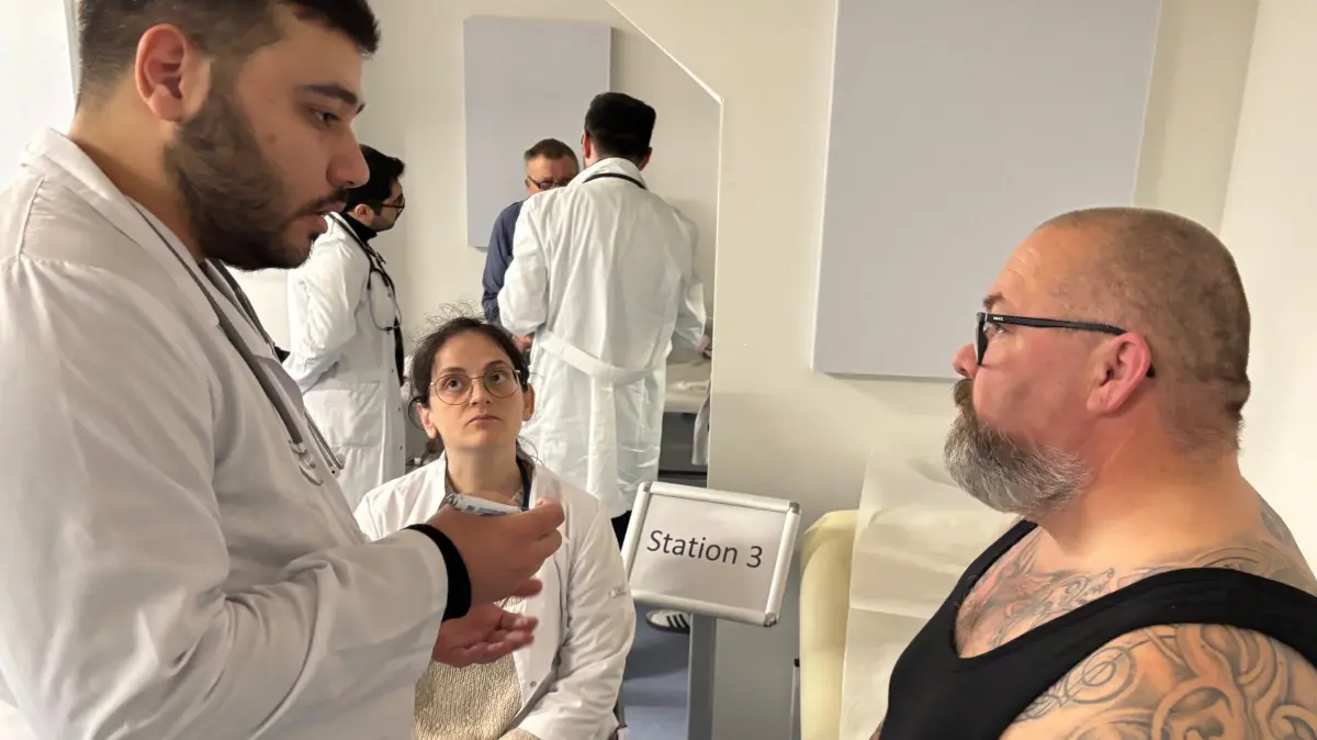 Was haben Sie für Beschwerden? Ai-Hamid Abd fragt den Simulationspatienten Thomas Pleier nach seiner Krankheit aus. Nadide Zubari (Mitte) hört genau zu. In der medizinischen Hochschule Brandenburg in Neuruppin gehört diese Patientenbefragung zum Vorbereitungskurs