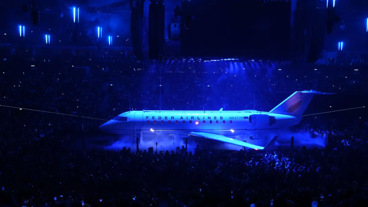 Mit einem lauten Knall fällt der Vorhang und enthüllt ein echtes Flugzeug. Mitten in der Uber Arena.