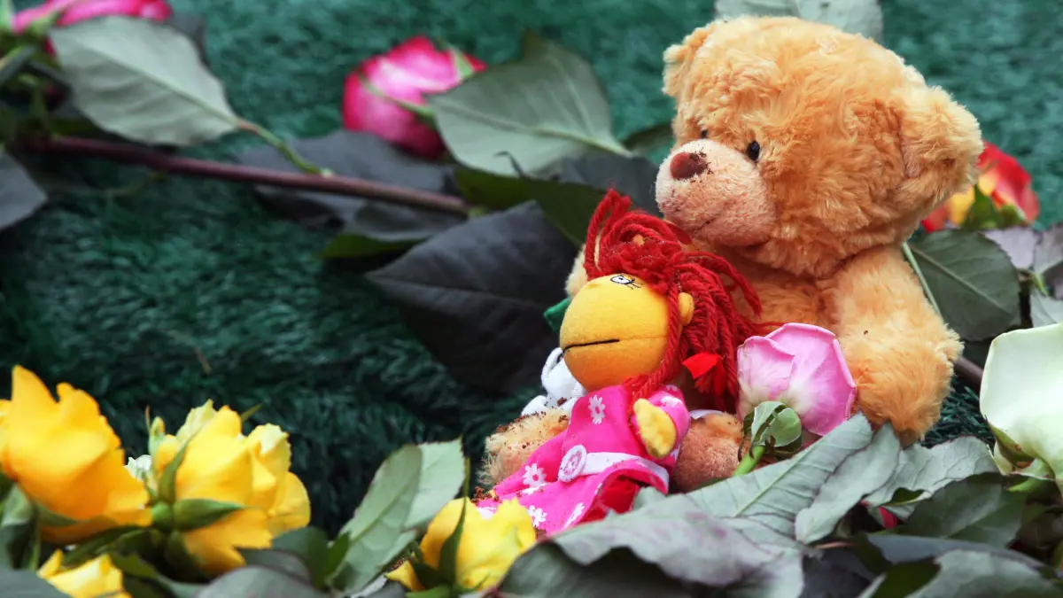 ARCHIV - Ein Teddybär und Blumen liegen am 29.11.2007 auf dem Waldfriedhof Schwerin auf dem Grab eines fünfjährigen Mädchens. Foto: Jens Büttner dpa (zu dpa "Wenn ein Kind stirbt - Verband bietet trauernden Eltern Hilfe" vom 28.07.2016) +++ dpa-Bildfunk +++