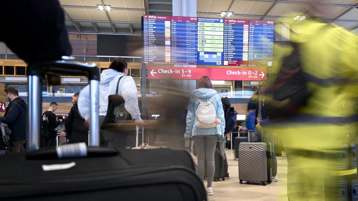 Flugreisende stehen vor der großen Anzeigetafel im Terminal 1 des Flughafens Berlin Brandenburg. Am Flughafen BER ist der Flugverkehr aufgrund der Witterung eingestellt worden. +++ dpa-Bildfunk +++