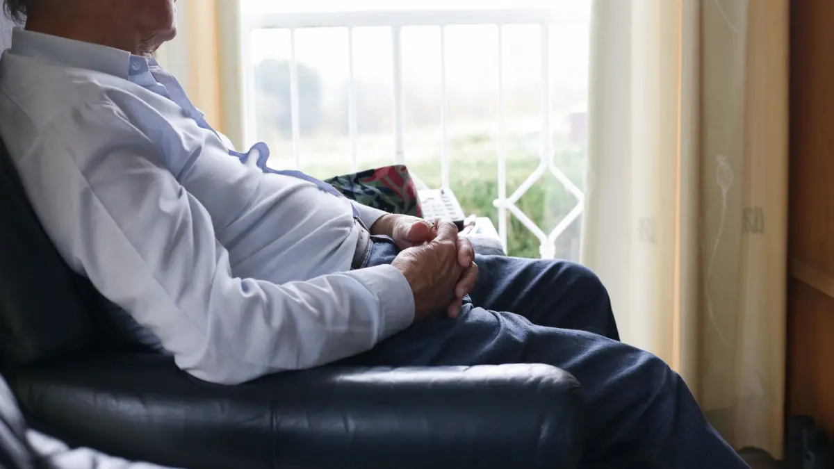 Senior sitzt zu Hause in einem Sessel