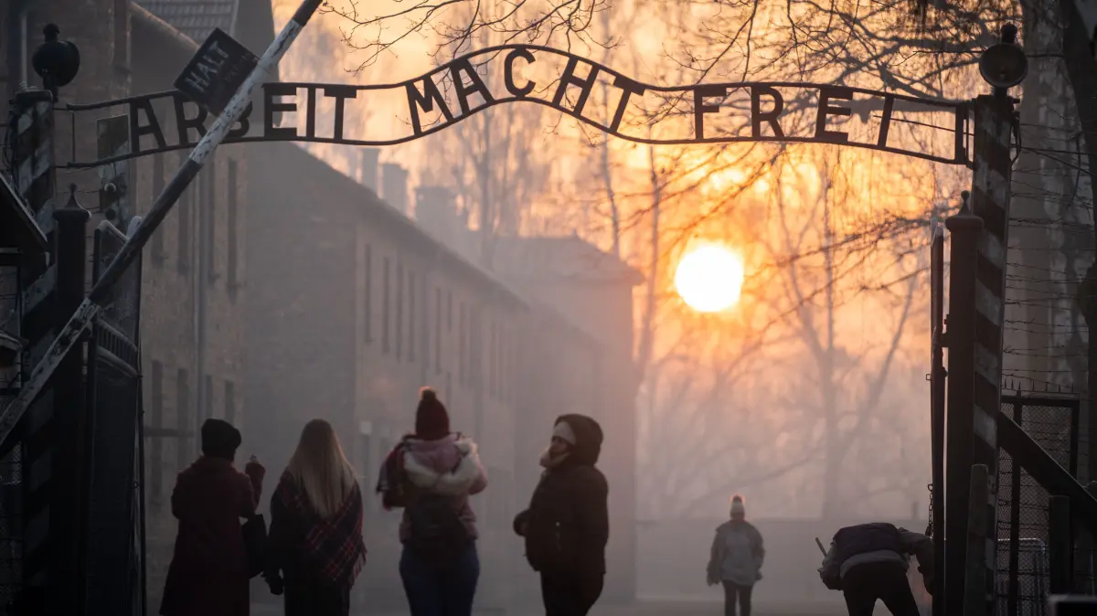 Besucher stehen am frühen Morgen am Tor zum früheren Konzentrationslager Auschwitz I mit dem Schriftzug "Arbeit macht frei".