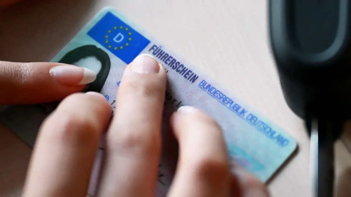 Führerschein: ILLUSTRATION - 10.02.2026, Berlin: Eine Frau legt ihren Führerschein auf einen Tisch, daneben liegt ein Autoschlüssel. Bundesverkehrsminister Schnieder stellt die weiterentwickelten Eckpunkte der geplanten Reform zur Modernisierung und Kostensenkung in der Fahrschulausbildung vor. Ziel der Reform ist es, den Erwerb des Führerscheins bezahlbarer zu machen, bei gleichbleibend hohen Standards der Verkehrssicherheit. Foto: Elisa Schu/dpa +++ dpa-Bildfunk +++
