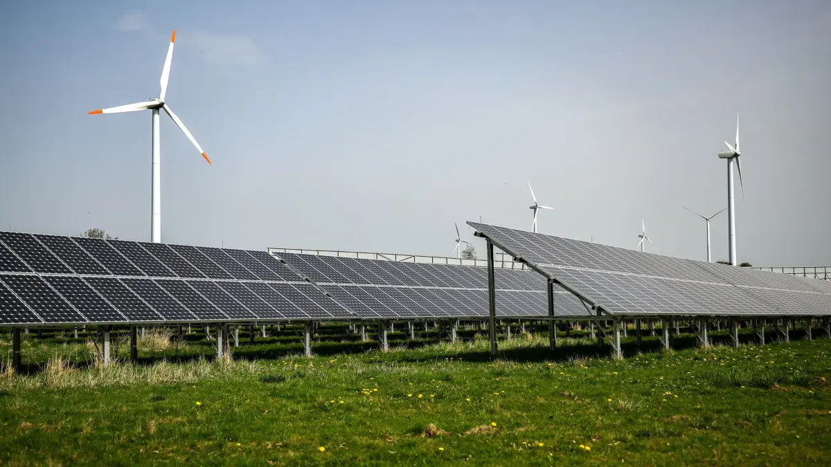 Windräder hinter Solaranlagen: ARCHIV - 08.04.2024, Sachsen, Leisnig: Mehrere Windkraftanlagen stehen hinter einem Solarpark.(Luftaufnahme mit Drohne) (zu dpa: «Studie: Weniger Rückhalt für die Energiewende») Foto: Jan Woitas/dpa +++ dpa-Bildfunk +++