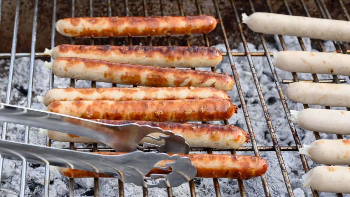 Trauerfeier für den Eberswalder Wurst-Traditionsbetrieb: 14.02.2026, Brandenburg, Britz: Eberswalder Würstchen liegen auf einem Grill bei der «Trauerfeier» für den Eberswalder Wurst-Traditionsbetrieb. Aufgerufen zur Demonstration hatte die Gewerkschaft Nahrung-Genuss-Gaststätten (NGG). Das Werk wird zweieinhalb Jahren nach der Übernahme durch den Tönnies Konzern geschlossen. Für Rostbratwürste ohne Darm und Knüppelsalami ist die Marke «Eberswalder» bekannt, manchen gilt sie gar als Kultmarke aus Ostdeutschland. Doch nach fast 50 Jahren ist für die traditionsreiche Wurstfabrik im brandenburgischen Britz bei Eberswalde nordöstlich von Berlin Schluss. Ende Februar endet die Produktion.. Foto: Patrick Pleul/dpa +++ dpa-Bildfunk +++