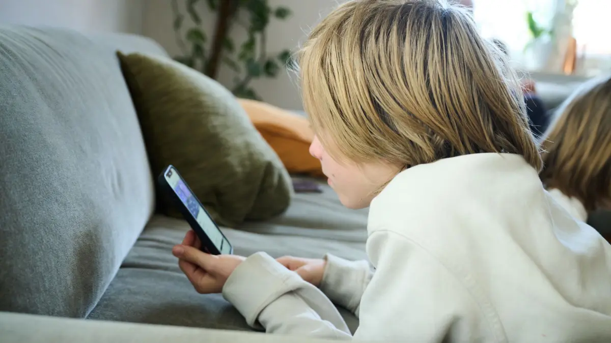Social-Media-Nutzung: ARCHIV - 21.04.2025, Bayern, Roth: ILLUSTRATION - Ein Junge liegt auf einem Sofa und guckt auf sein Smartphone. (gestellte Szene). (zu dpa: «SPD will Social-Media-Verbot für Kinder unter 14») Foto: Annette Riedl/dpa +++ dpa-Bildfunk +++